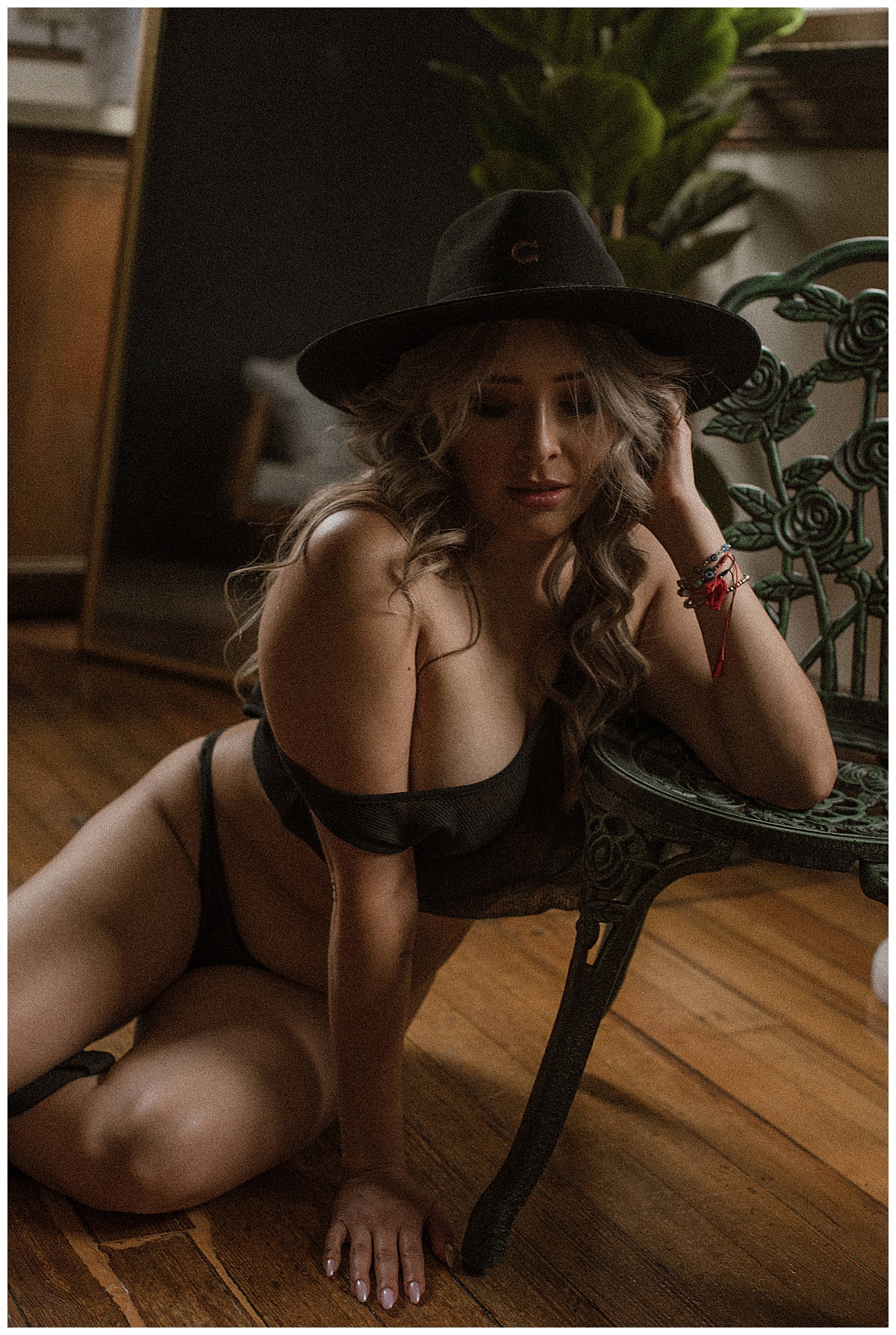 Woman lays on the floor wearing a cowboy hat for Colorado Boudoir Photographer