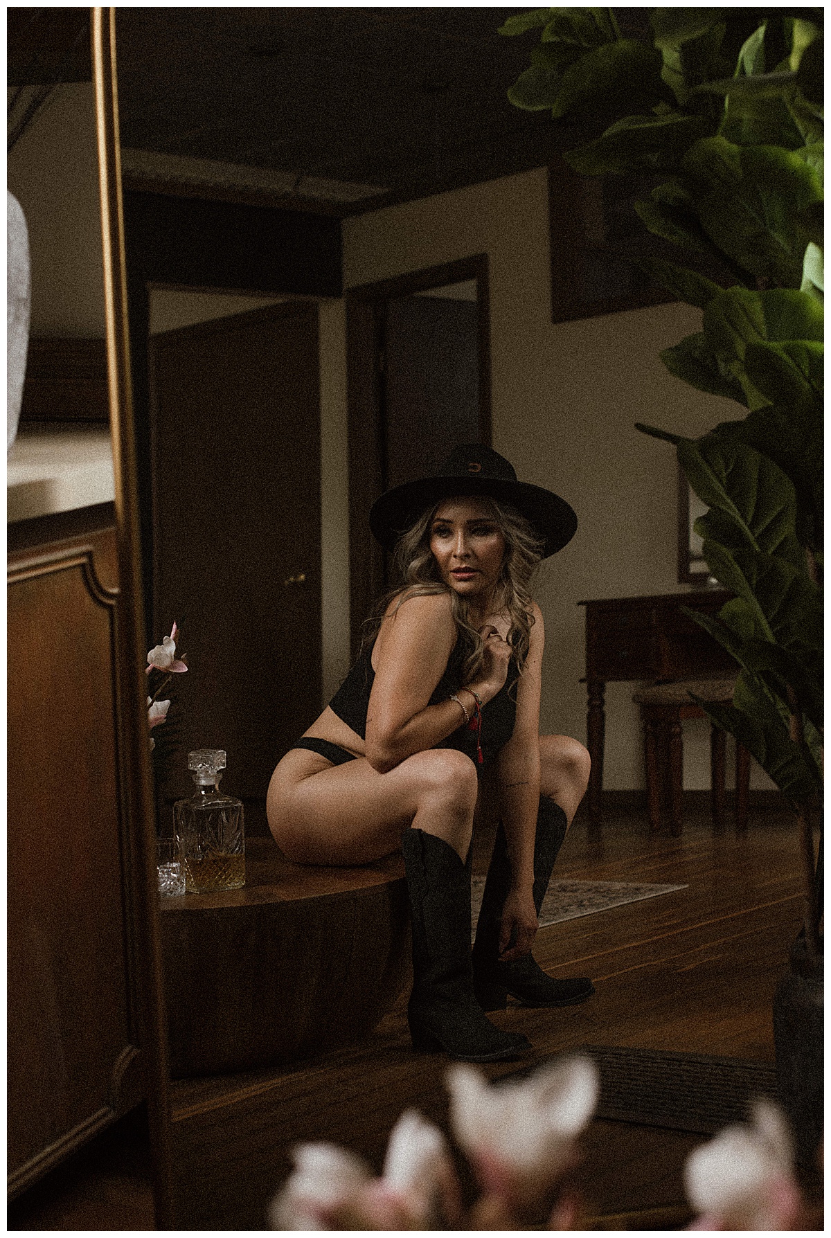 Adult sits on a bench wearing a cowboy hat showing off a fun Lingerie Theme 